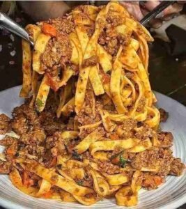 Macarrão talharim à bolonhesa servido com molho e queijo