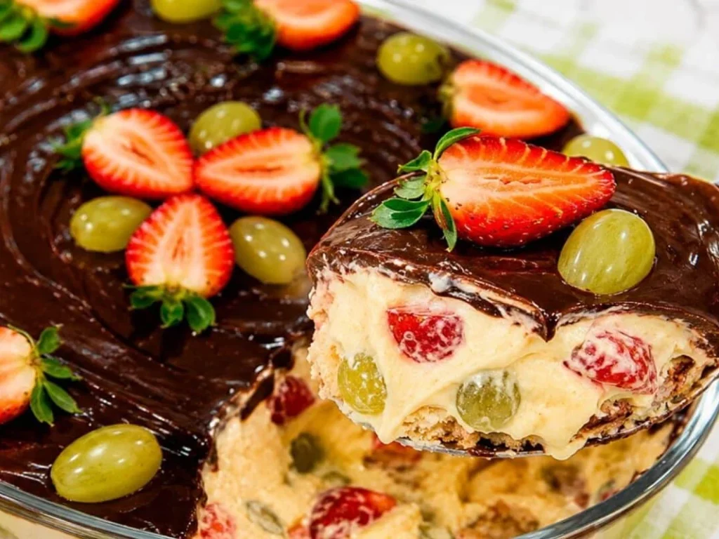 Bombom aberto na travessa com morango e uva, creme aveludado e cobertura de chocolate